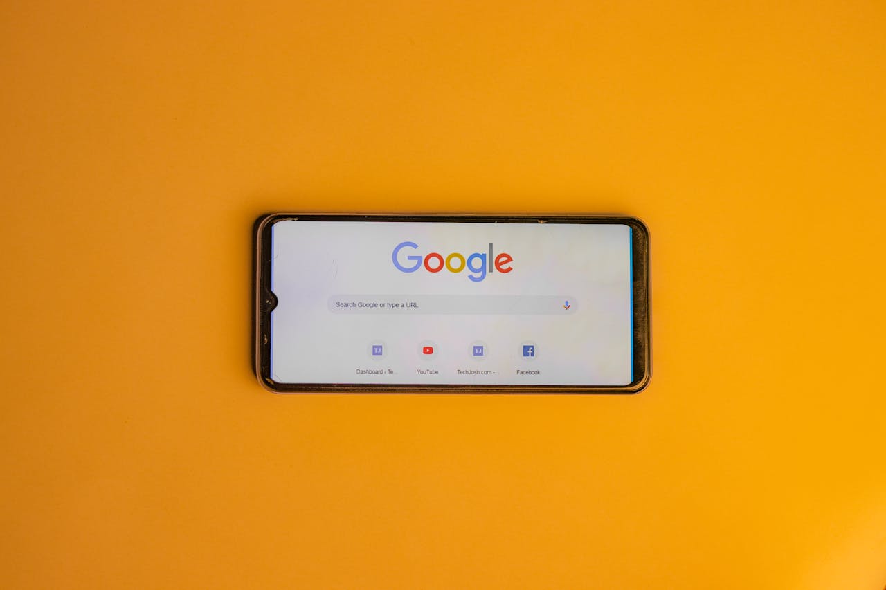 Smartphone displaying Google search page on a vibrant yellow background.